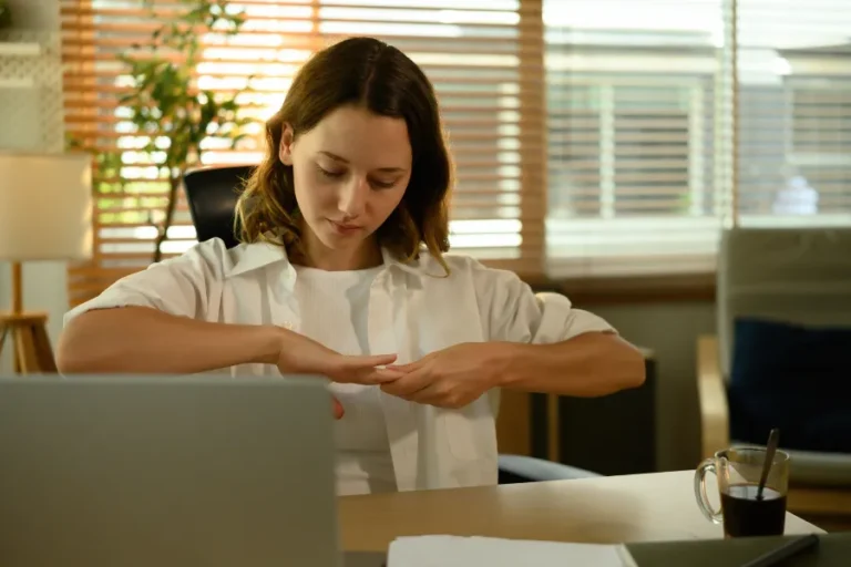 Woman in front of laptop holding her wrist