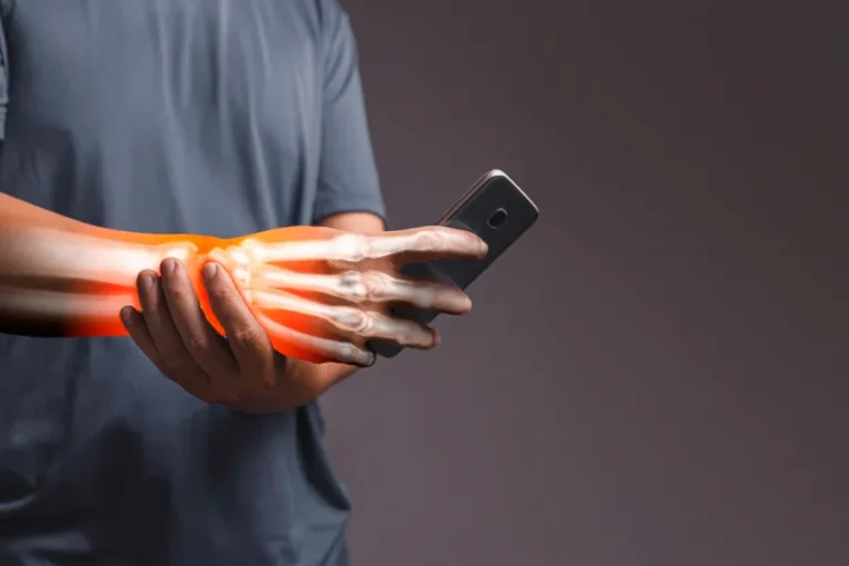 Red glow around a mans wrist while holding a cell phone